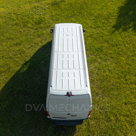 Aerial rear view of a white Mercedes Sprinter on grass with LoadSpan roof rails mounted along the roof edges