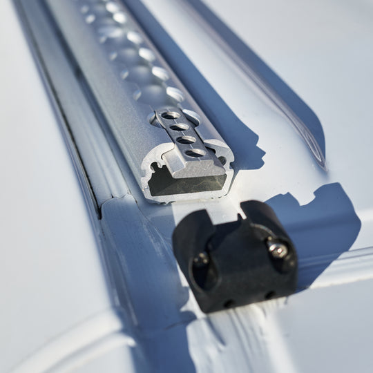 Macro detail of the LoadSpan L-track channel with a T-bolt anchor stud and black L-track fitting engaged